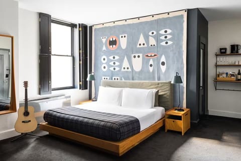 Stretch out in a spacious, art-filled bedroom with warm lighting.