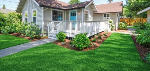 A cozy retreat surrounded by greenery, featuring a sunny porch and beautiful landscaping that invites you to slow down and unwind.
