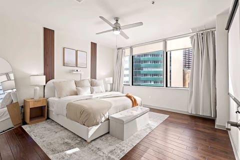 Inviting bedroom with large windows offering city views and abundant natural light. Stylish furnishings and soft textures create a calm atmosphere perfect for restful nights and relaxed mornings.