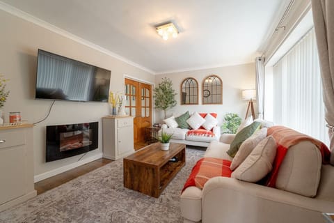 Bright lounge with two sofas, a coffee table, and a wall-mounted TV above a fireplace