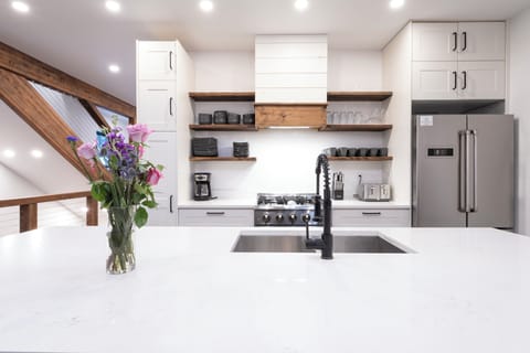 Your modern kitchen awaits with sleek white countertops, stainless steel appliances, and warm wood shelving for all your culinary adventures.