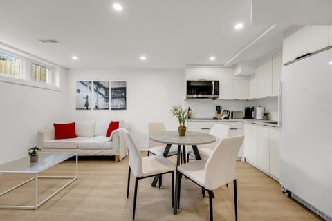 Bright and modern open-concept space featuring a cozy seating area, dining table, and fully-equipped kitchen with stainless steel appliances. Perfect for cooking and relaxing.