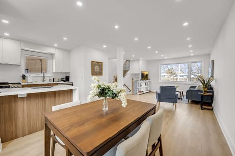 Stunning open-plan main level featuring a sophisticated dining area with seating for six, stylish living room seating, and a view of the breakfast bar/kitchen.