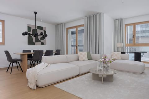 Spacious living room with sofa, dining area and large windows.