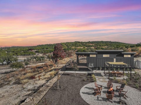 Wild Arrow Ranch nestled in rolling hills with fire pit area under sunset skies.