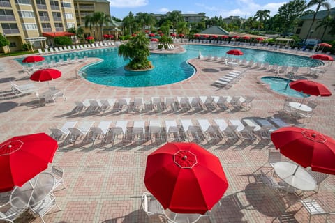 Bright red umbrellas offer shade around the inviting resort pool area.
