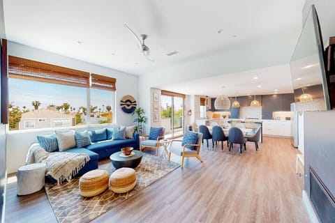 Bright and stylish living area with cozy seating, gas fireplace, and Smart TV—perfect for relaxing after the beach. Open-concept design flows into the kitchen and balcony, creating a comfortable space to unwind and enjoy coastal vibes.