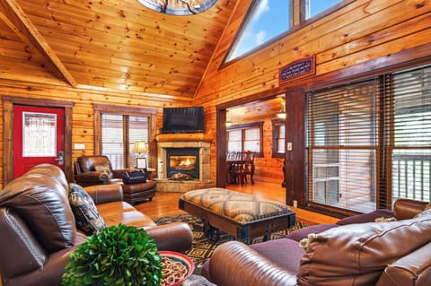 Main living area featuring vaulted ceilings, a stone fireplace, and rustic decor.