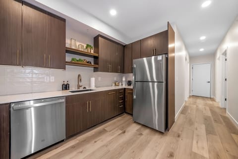 Your modern kitchen features rich walnut cabinets, stainless steel appliances, and elegant white quartz countertops—perfect for preparing meals in style.