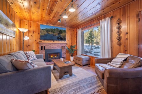 You'll love this warm and inviting living room framed by the large window showing forest views.