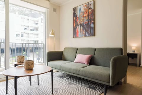 Relax in this stylish living room with a comfy sofa and vibrant city views, perfect for unwinding after a day of exploring.