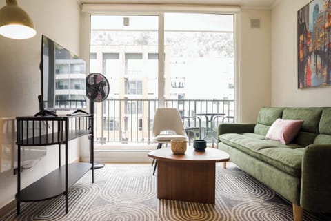 Relax in this cozy living room with a comfy green sofa and enjoy the view from the large windows.