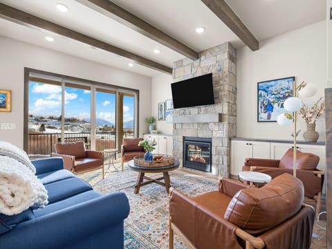 Primary living room at Summit View Lodge with large cozy gas fireplace, large smart TV, ample luxurious seating and a large amazing deck with unobstructed views of Mount Timpanogos