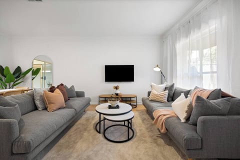 Settle into the light-filled living area, where soft seating and calm styling invite you to unwind after a day exploring the city.