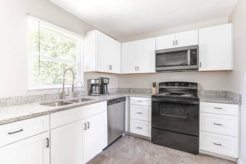 Full kitchen with range, microwave, dishwasher and coffee makers. Ample cabinets and worktop areas, with double sink.