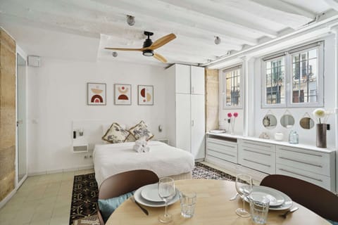 Pièce de vie lumineuse avec un lit queen size, TV et table à manger