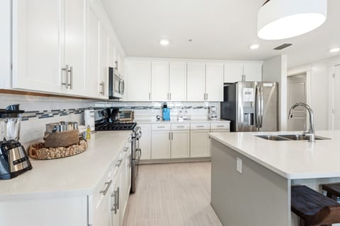 Your spacious kitchen awaits with gleaming white cabinets, stainless steel appliances, and ample counter space for cooking memorable vacation meals.