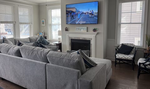 Living room with fireplace, large TV, wine fridge & new (2026) sectional.