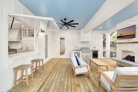 Unwind in your stylish outdoor living space featuring a cozy fireplace, outdoor kitchen, and comfortable seating perfect for entertaining.