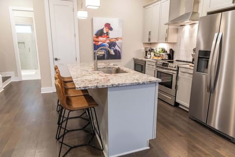 Sleek, modern kitchen with granite island and guitar-inspired art.