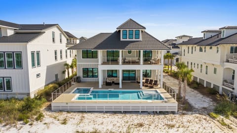 Stunning beachfront architecture with your private pool and hot tub steps from the sand, framed by a covered veranda and surrounded by swaying palms under endless blue skies.
