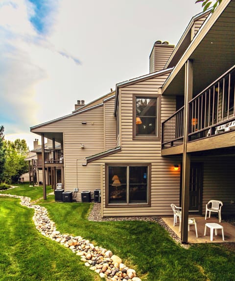 Rear view of a multi-level building with balconies and a neatly landscaped lawn.