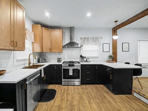 Modern kitchen w/ wood cabinets, white counters & black accents