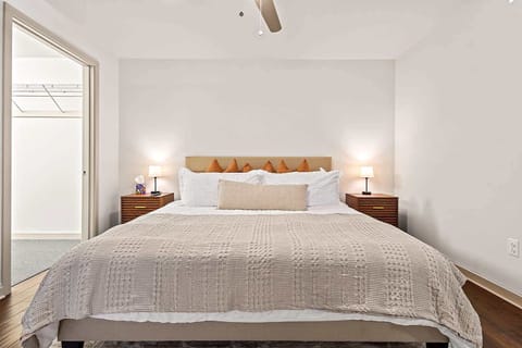 Bright and inviting bedroom featuring a comfortable bed with crisp linens, plush pillows, and warm wood flooring. Soft lighting and a clean, minimalist design create a relaxing atmosphere ideal for restful nights and extended stays.