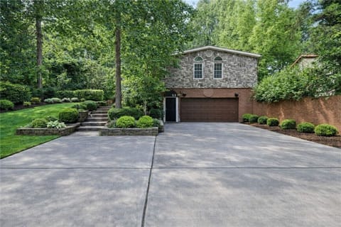 Welcome guests with an expansive driveway for easy parking, set against a beautifully landscaped facade with stone accents and lush greenery.