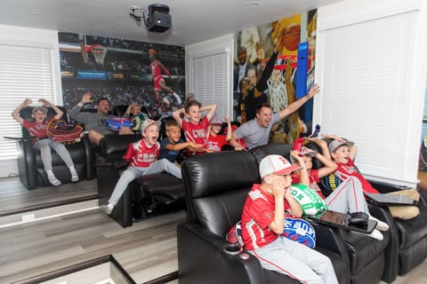 Cheer with your crew in this ultimate sports fan cave, featuring leather recliners and basketball action on every wall.