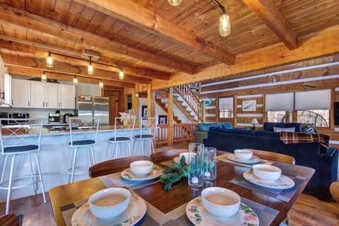 Gather around this rustic dining table where exposed beams and warm wood create your perfect mountain retreat atmosphere.