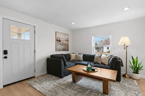 Unwind in this cozy living area featuring a plush sectional, warm wood accents, soft lighting, and natural light that creates a calm, inviting retreat.