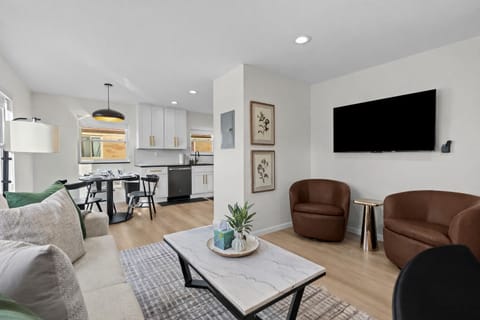 Modern open living space with cozy seating, smart TV, and seamless flow to kitchen and dining—bright, stylish, and perfect for relaxing or entertaining.