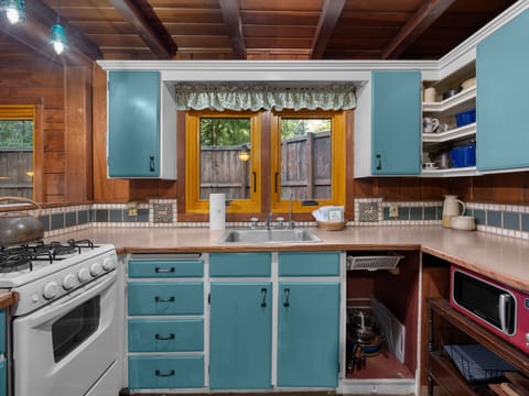 Step into your charming kitchen with exposed beams, cheerful turquoise cabinets, and everything you need to cook memorable meals together.