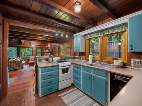 Your charming kitchen features turquoise cabinets, exposed beams, and forest views that create a cozy cooking haven.