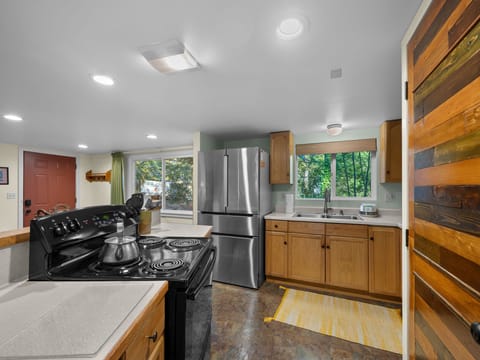 Your fully equipped kitchen features stainless steel appliances and warm wood accents, perfect for preparing meals with views of the lush surroundings.