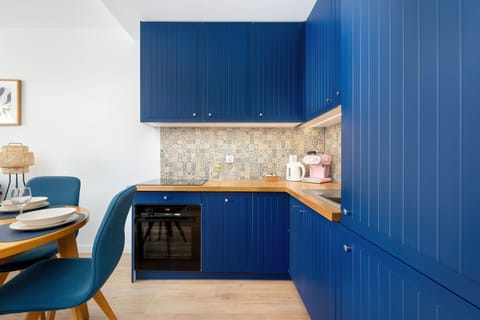 Contemporary kitchen with deep blue cabinets, wooden countertop, and built-in appliances.