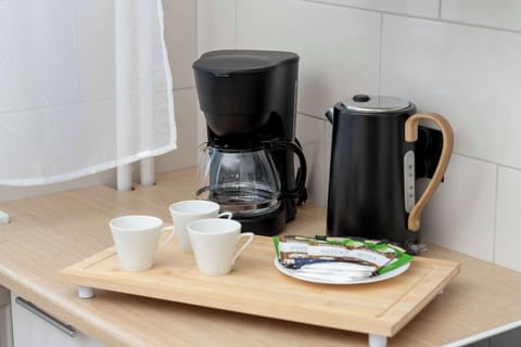 A close-up of the kitchenette counter with a coffee maker, electric kettle, and cups. It highlights the practical amenities provided for guests.