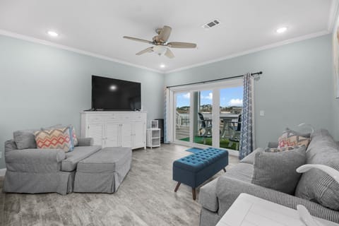 Spacious living room at Pescador Landing in Perdido Key, FL – just minutes from FloridaBama. Relax on plush sofas under the ceiling fan, with a large flat-screen TV perfect for unwinding after a day at the beach.
