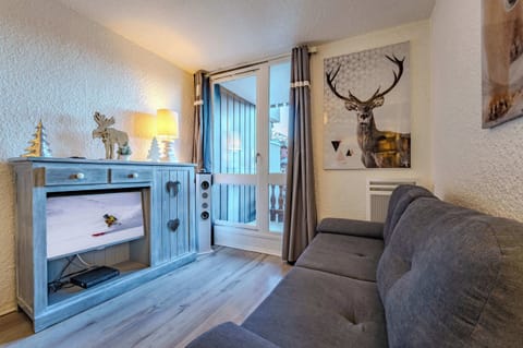 Relaxing lounge with TV, mountain décor, and direct balcony access — enjoy stunning Val Thorens sunsets.