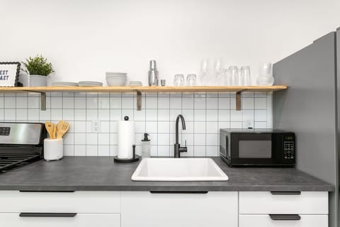 Kitchen with open shelving, microwave, and essentials for easy meal prep.