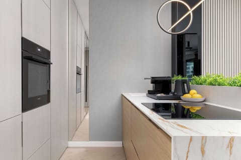 A narrow kitchen perspective showing cabinetry, countertop, and integrated appliances. Vertical wall panels add visual interest. The space looks efficient and well-organized.
