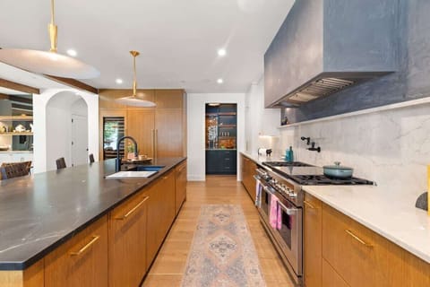 This chef’s kitchen boasts Wolf appliances, dual dishwashers, twin Sub-Zero fridge and freezer, warming drawer, wine fridge, and a sleek island with seating. Marble and wood finishes pair with designer lighting for a refined, modern feel.