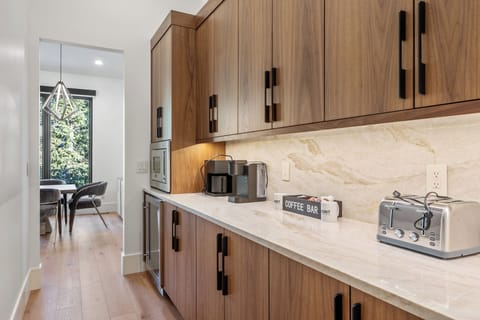 Convenient main-floor coffee and prep area with generous counter space, cabinetry, and small appliances—perfect for morning coffee or extra serving space when entertaining.