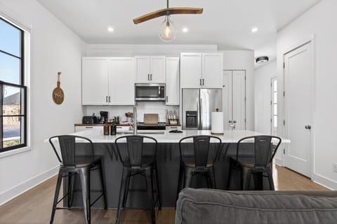 Modern kitchen featuring white cabinetry, dark island, and industrial bar stools.