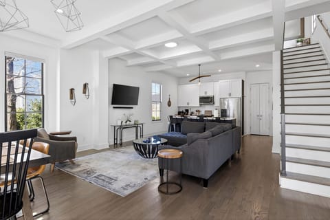 Large open-concept living room with a dark sectional sofa and coffered ceilings.
