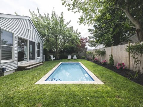 Sunlit backyard pool area framed by vibrant landscaping and comfortable seating.