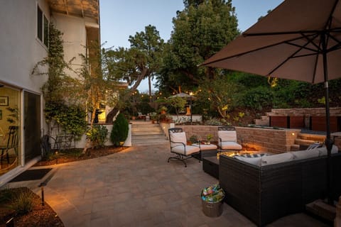 Inviting backyard retreat with layered patio seating, ambient lighting, and a warm fire feature. Ideal for evening gatherings and relaxed outdoor living.