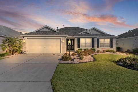 A beautiful single-story home with manicured landscaping welcomes guests under dramatic sunset skies in this peaceful residential neighborhood.