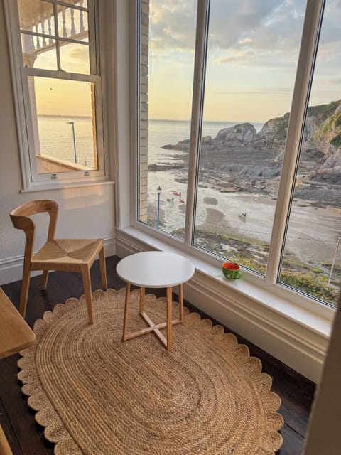 Combe Martin Bay at low tide as seen from floor to ceiling windows. Paddle boarders return to the shore.